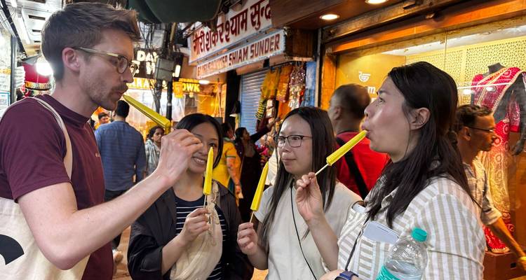 Four people enjoying street food in a busy market.