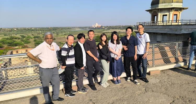 Group of people posing in front of a scenic view with a distant landmark.