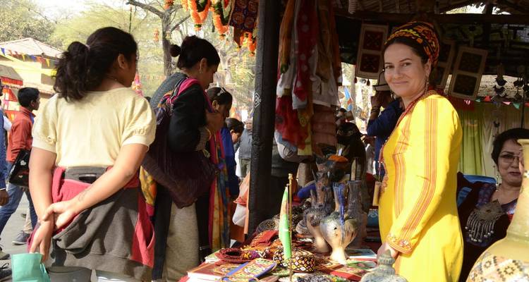 Market scene with colorful textiles and a smiling vendor.