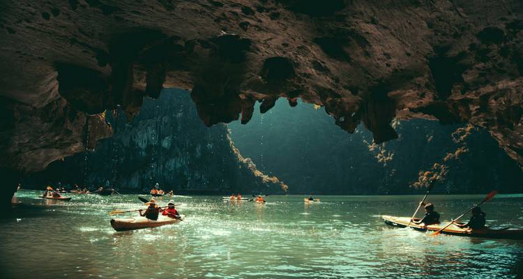 Des kayakistes pagayant sous une grotte dans la baie d'Halong.