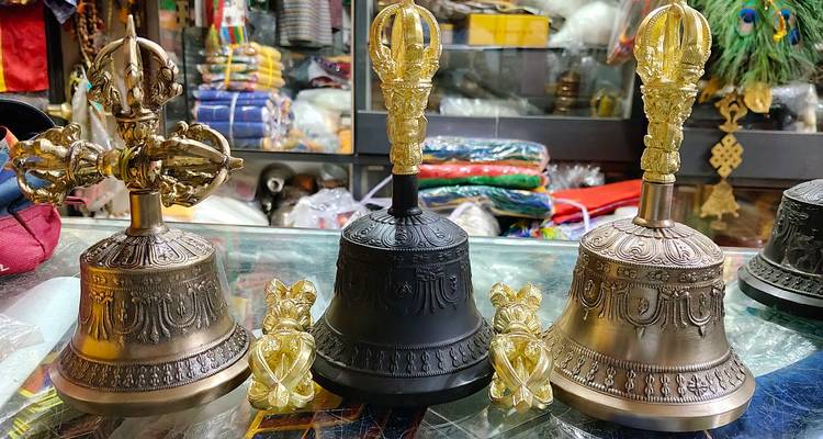 Display of ornate Tibetan ritual bells and dorje sceptres on glass counter in shop
