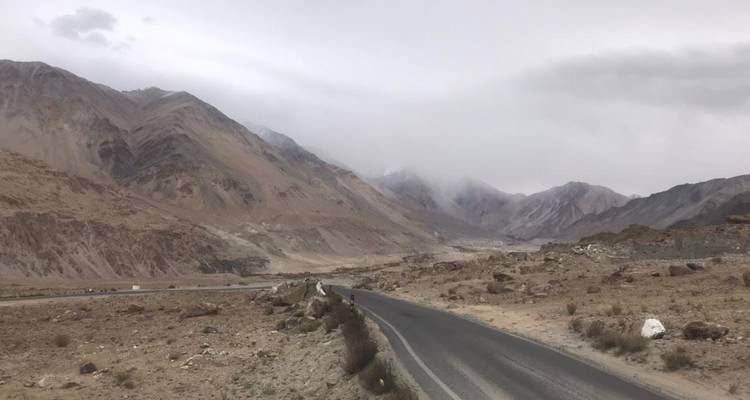 Mountain road with barren landscape and cloudy sky.