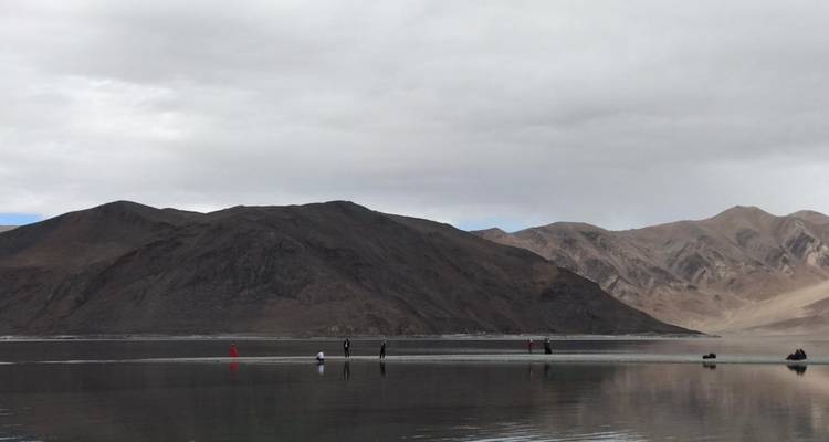 People walking on a frozen lake with mountains in the background.