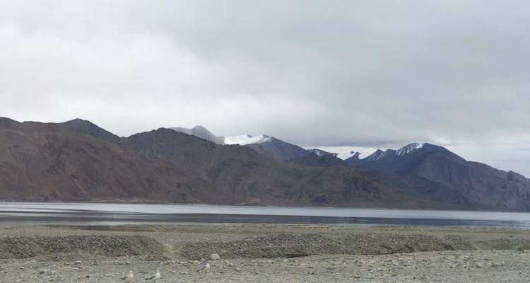 Lake with distant mountains under a cloudy sky.