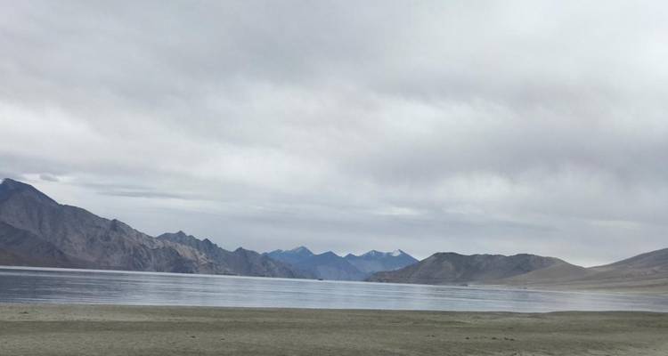 Mountain lake surrounded by distant mountain range.