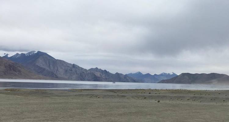 Scenic view of a lake with mountains and cloudy sky.