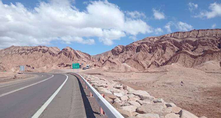 Road through desert landscape with mountainous backdrop, possibly in Atacama Desert.