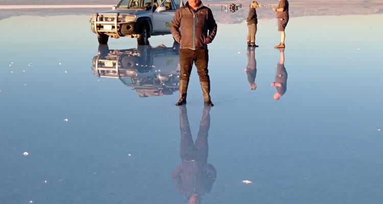 People and vehicle with reflection on the Uyuni Salt Flats.