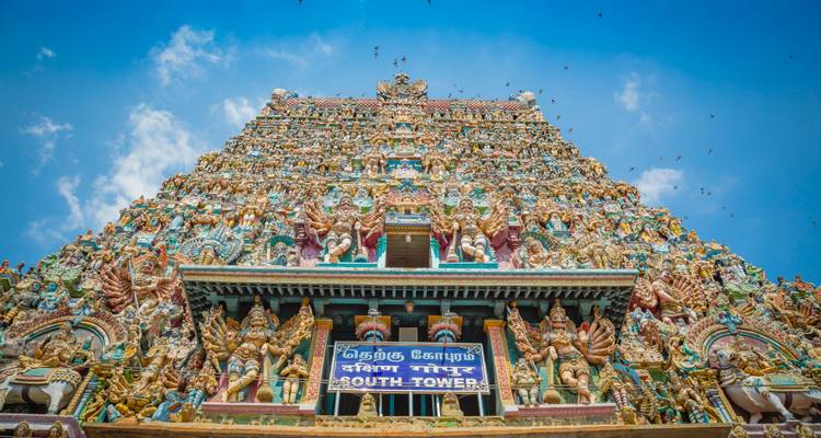 Intricately carved temple tower against a blue sky.