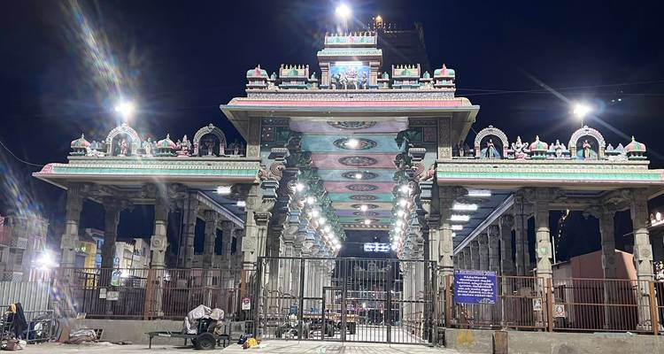 Illuminated entrance mandapam of a South Indian temple complex at night with starburst lights.