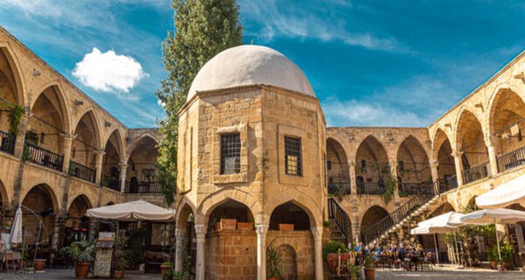 Stone-built caravanserai courtyard with a central domed kiosk under a vivid blue sky
