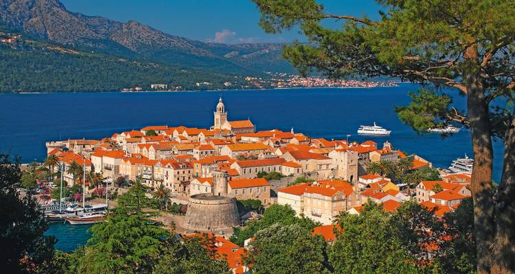 Luftaufnahme einer historischen Küstenstadt mit einem Yachthafen.