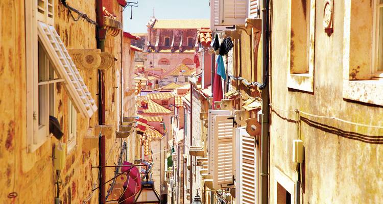 Schmale Gasse mit bunten Gebäuden und geschlossenen Fensterläden.