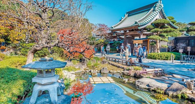 Ein traditioneller japanischer Garten mit einem Teich und Besuchern.
