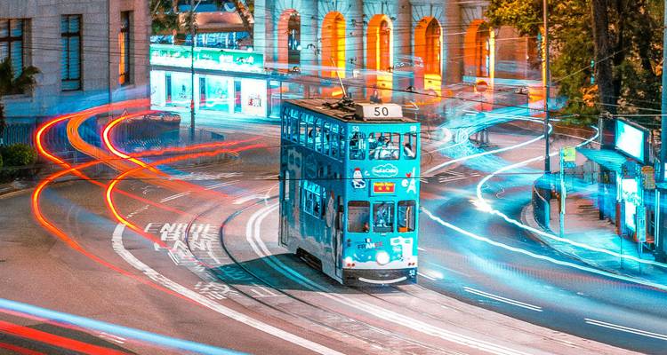 Eine Straßenbahn, die nachts durch eine Stadtstraße mit hellen Lichtern fährt.