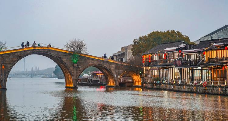 Historische Brücke über einen Fluss mit traditionellen Gebäuden an der Seite.