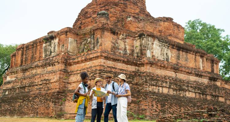Gruppe von Touristen, die mit einer Karte antike Ruinen erkundet.