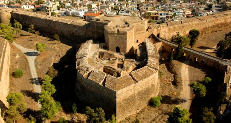 Historical fortress with walls and towers in a dry landscape.