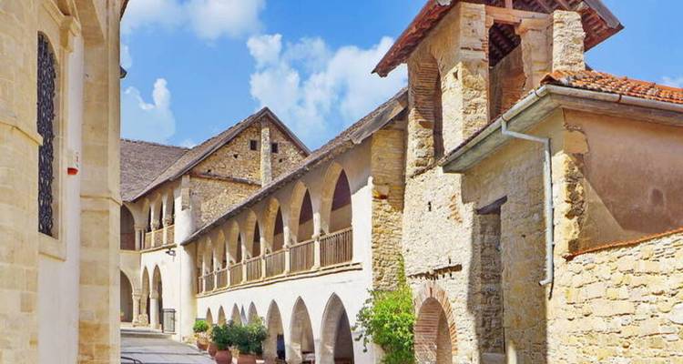 Long arched cloister of a stone mountain monastery under a bright sky.