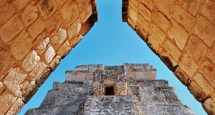 Ein Blick auf eine Maya-Pyramide durch steinerne Torbögen.