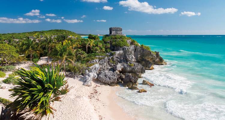 Unberührter Strand mit türkisfarbenem Wasser und einer historischen Ruine.
