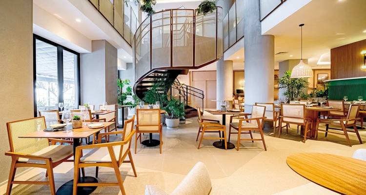 Innenraum eines stilvollen Essbereichs mit großen Fenstern.