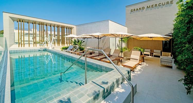 Dachterrassen-Poolbereich mit Sonnenliegen und Sonnenschirmen.