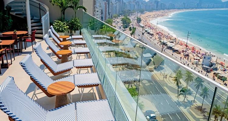 Strandblick von einer Terrasse mit Liegestühlen.