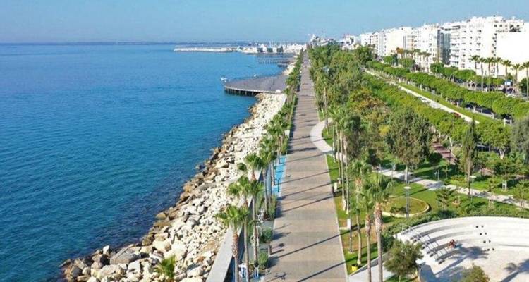 Long seaside promenade lined with palms and parks stretches along the bright blue Mediterranean.