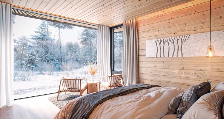 Innenraum einer modernen Hütte mit malerischem Schneeblick durch große Fenster.