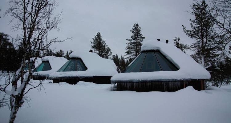 Schneebedeckte Hütten mit pyramidenförmigen Dächern.