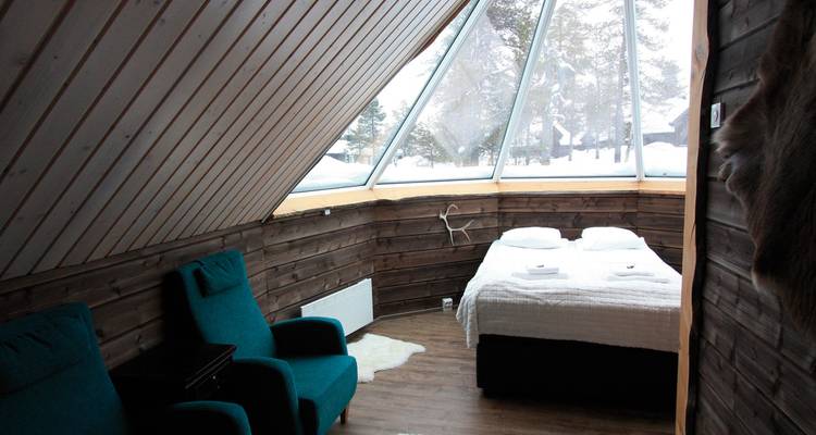 Innenraum einer Hütte mit großen Fenstern und zwei Stühlen.