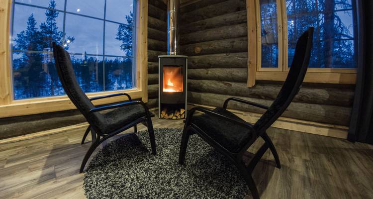 Gemütliches Hütteninterieur mit einem Kamin und Stühlen.