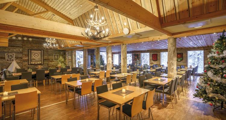 Essbereich mit Holzstühlen und Tischen in einer Blockhütte.