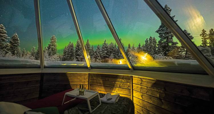 Aurora borealis betrachtet durch das Glasdach einer gemütlichen Hütte.