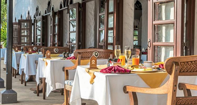 Dining setup with tables set for breakfast on a terrace.
