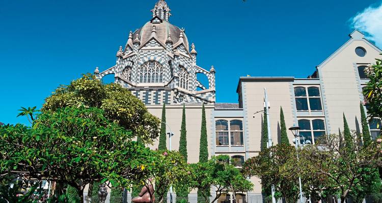 A cathedral with a distinct dome and clock tower surrounded by trees.