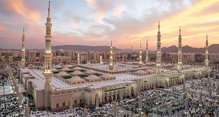 Grand mosque complex bustling with people at sunset