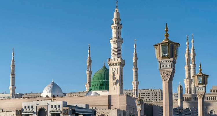Die grüne Kuppel einer Moschee mit mehreren Minaretten vor einem blauen Himmel.