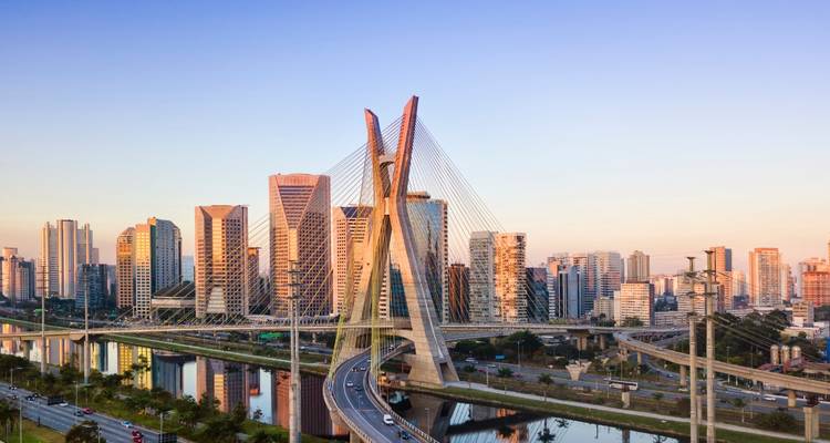 Moderne Skyline mit einer markanten Schrägseilbrücke bei Sonnenuntergang.
