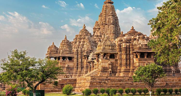 Ornate sandstone temples of Khajuraho complex under a bright sky.