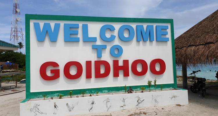 Groot kleurrijk welkomstbord voor het eiland Goidhoo tegen een tropische achtergrond