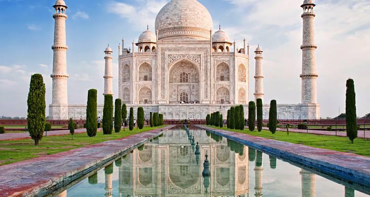 Le Taj Mahal se reflétant dans un long cours d'eau sous un ciel dégagé.