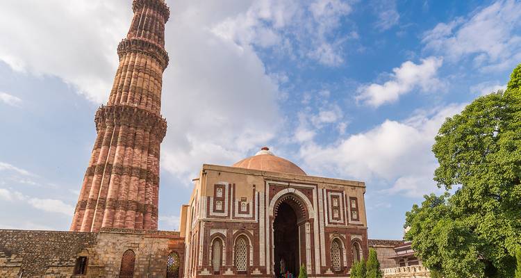 La tour Qutub Minar s'élevant majestueusement à côté de la porte ornementée Alai Darwaza sous un ciel lumineux