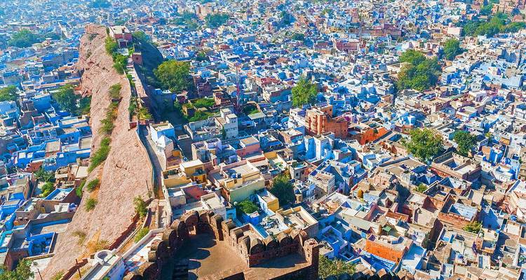 Une vue aérienne brillante de la vieille ville peinte en bleu de Jodhpur avec le long rempart du fort de Mehrangarh traversant le cadre.