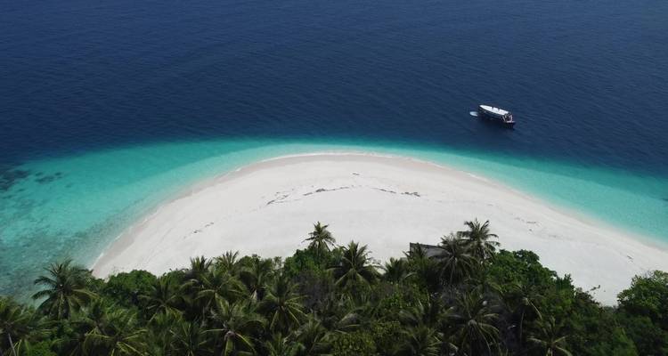 Vista aérea de una pequeña playa aislada con un barco cerca