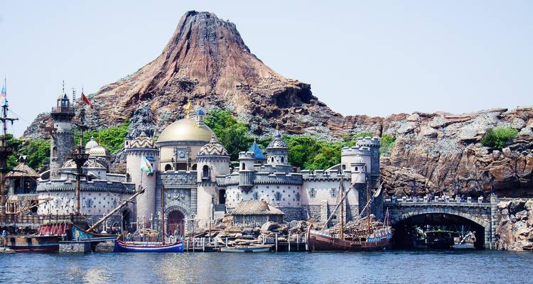 Theme park with a castle and a volcano-like mountain.