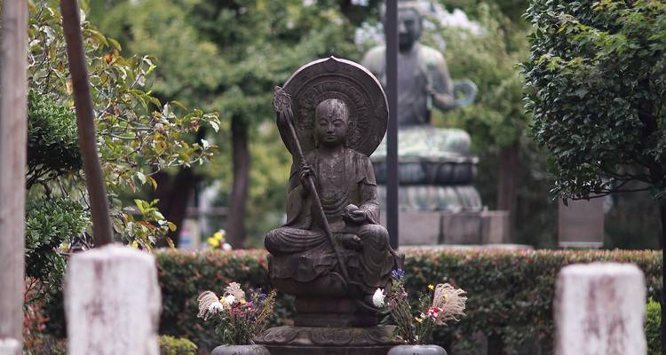 Statue in a garden with another statue in the background.