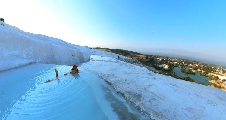 Un viajero se baña en las piscinas termales de color azul pálido de las terrazas de travertino de Pamukkale.