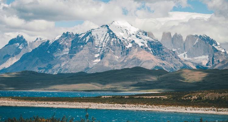 Montañas con nieve y un río en primer plano.
